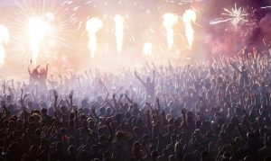Cheering crowd at concert in front of stage with pyrotechnics